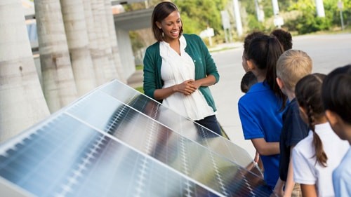 Woman educating a group of children about solar panels