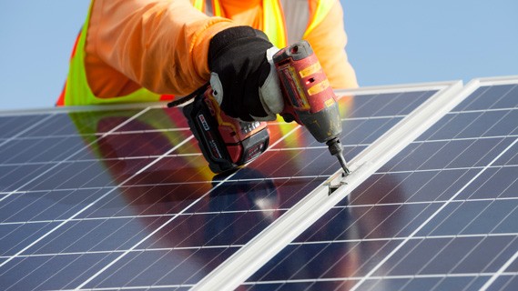 Employee drilling into solar panel